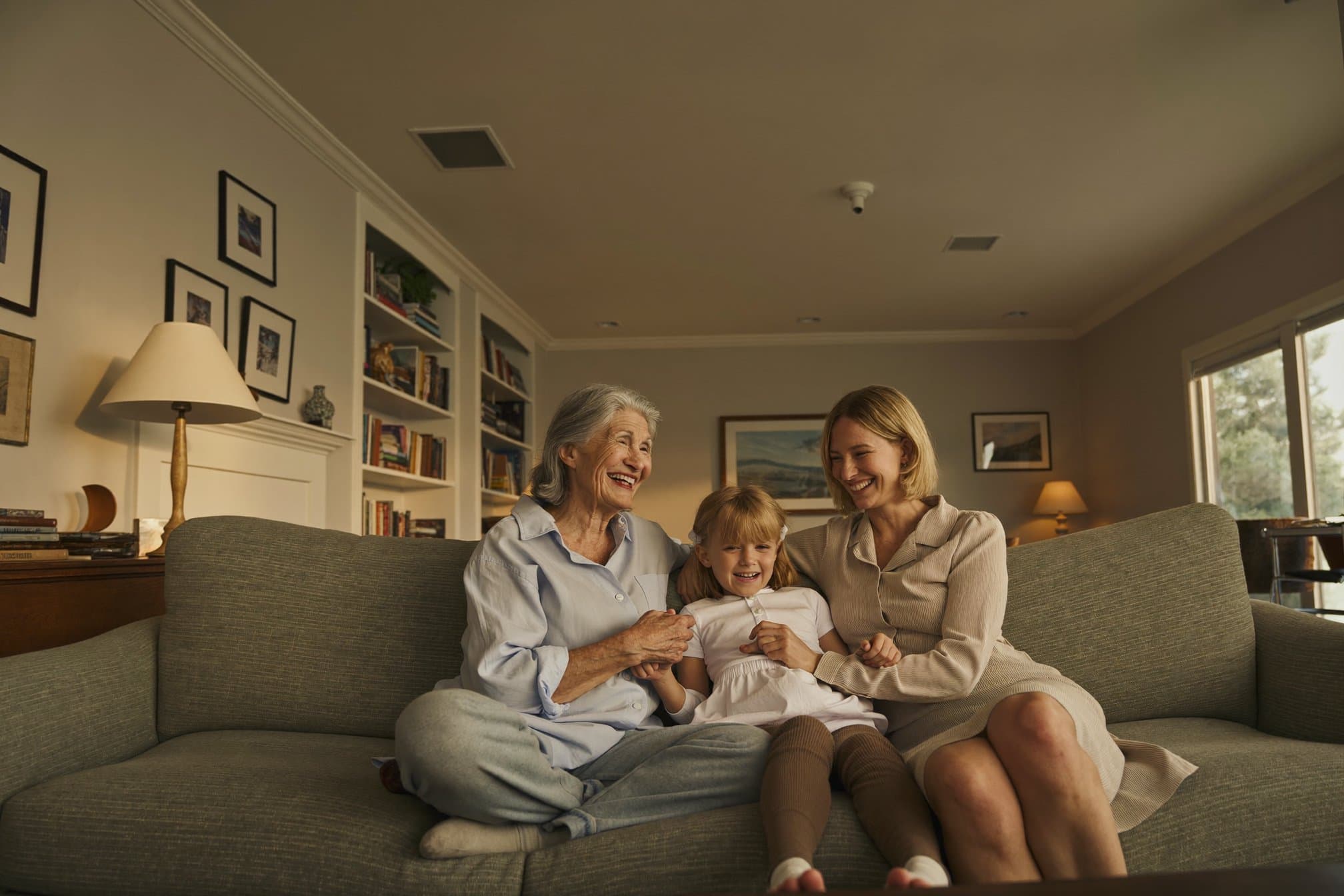 A family laughing together while visiting their mother in a warm residential living room - illustrative